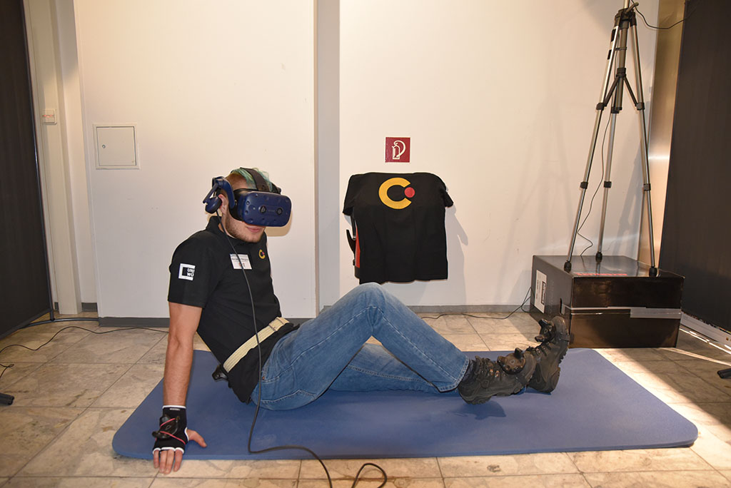 Mit den Trackern an Hand und Fuß ist Felix Totzauer von der Uni Würzburg bestens fürs Fitness vorbereitet. Durch die VR-Brille weiß er, ob er die Übungen richtig durchführt. (Bild: FAU/Rebecca Kleine Möllhoff)