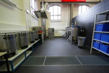 Ein Raum mit Regalen, in denen Kessel aus Metall und blaue Kisten aus Plastik stehen.