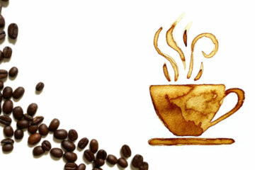 Tasse mit Kaffee, daneben liegen Bohnen