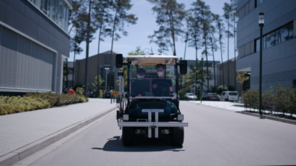 Ein autonomfahrendes Auto fährt auf einer Straße, es sitzen zwei Personen darin.