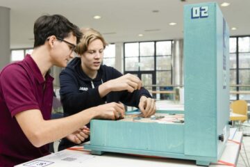 Zwei Personen testen eine Station des Lernlabors, sie stecken Kabel in verschiedene Anschlüsse.