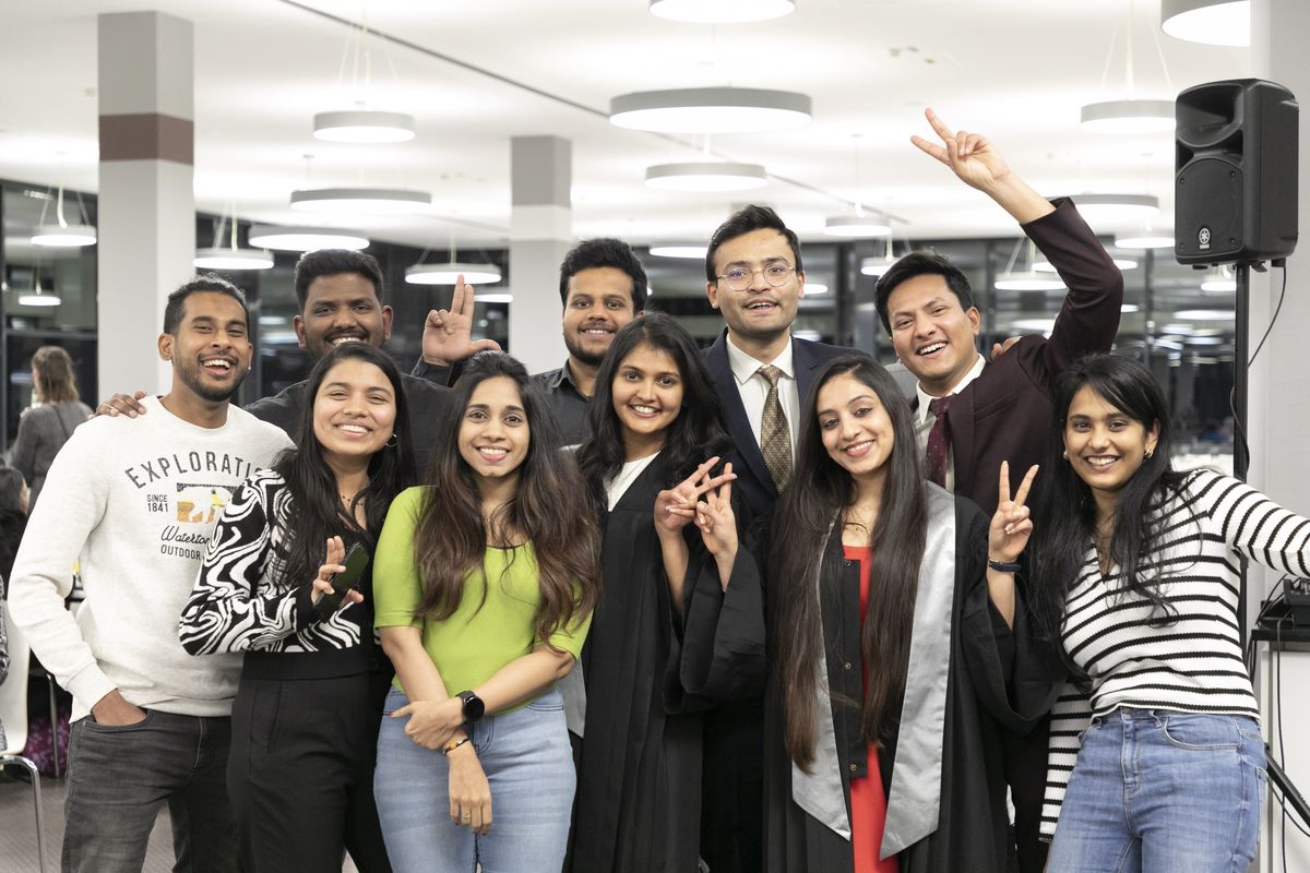 Mehrere Personen stehen beieinander und schauen freudig in die Kamera.