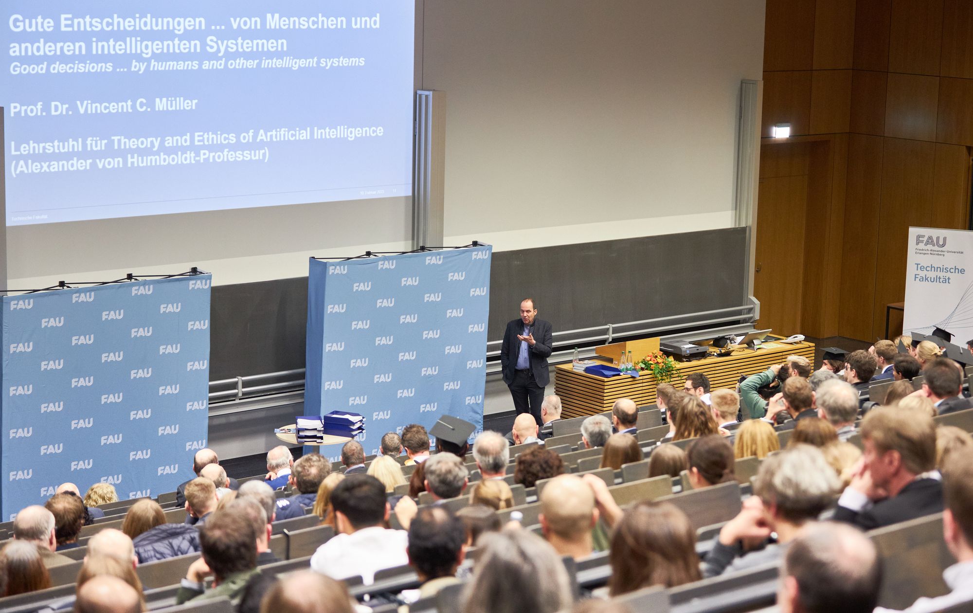 Ein Hörsaal in dem viele Menschen sitzen und einem Vortrag zuhören.