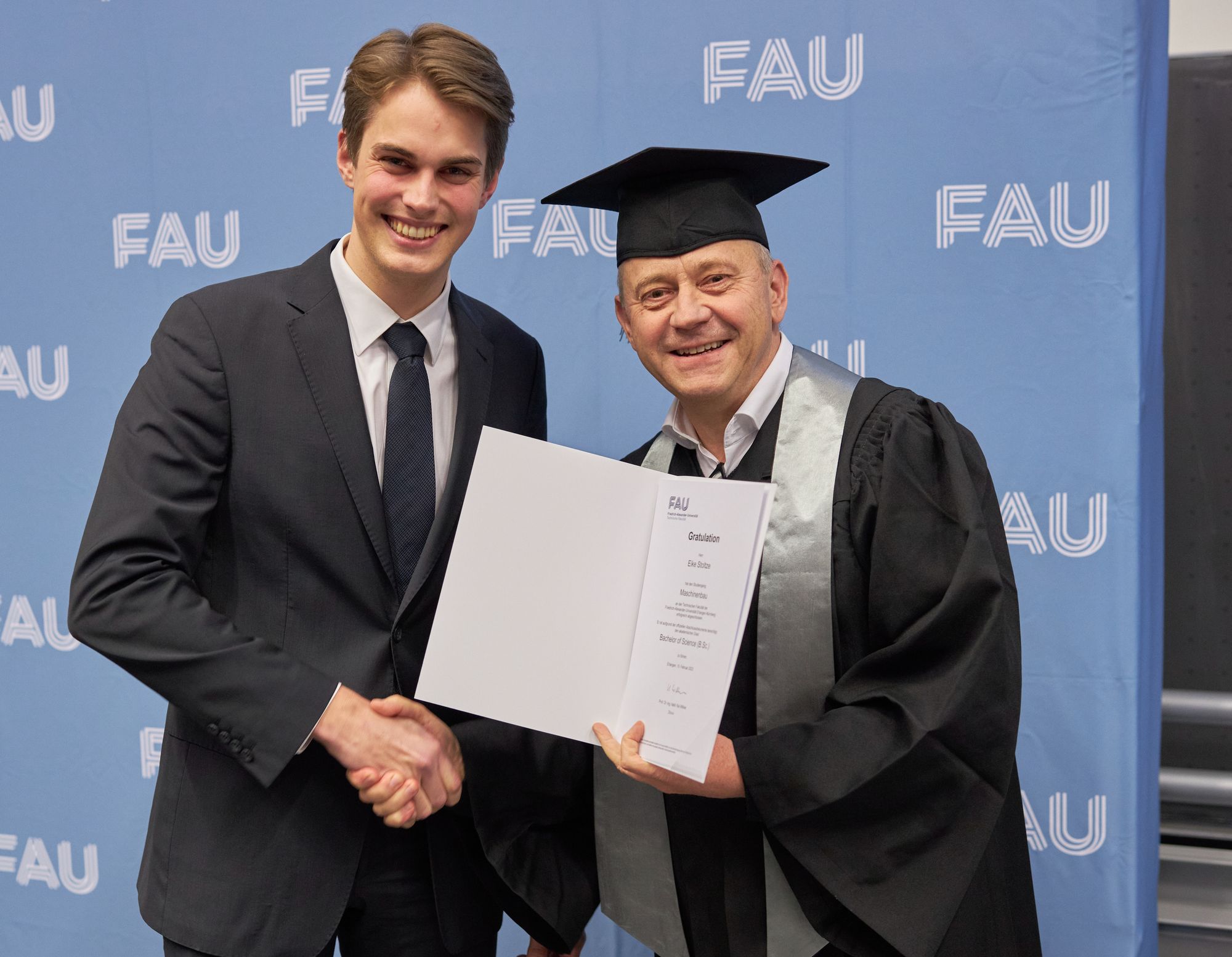 Überreichung der Urkunde an einen Absolventen.