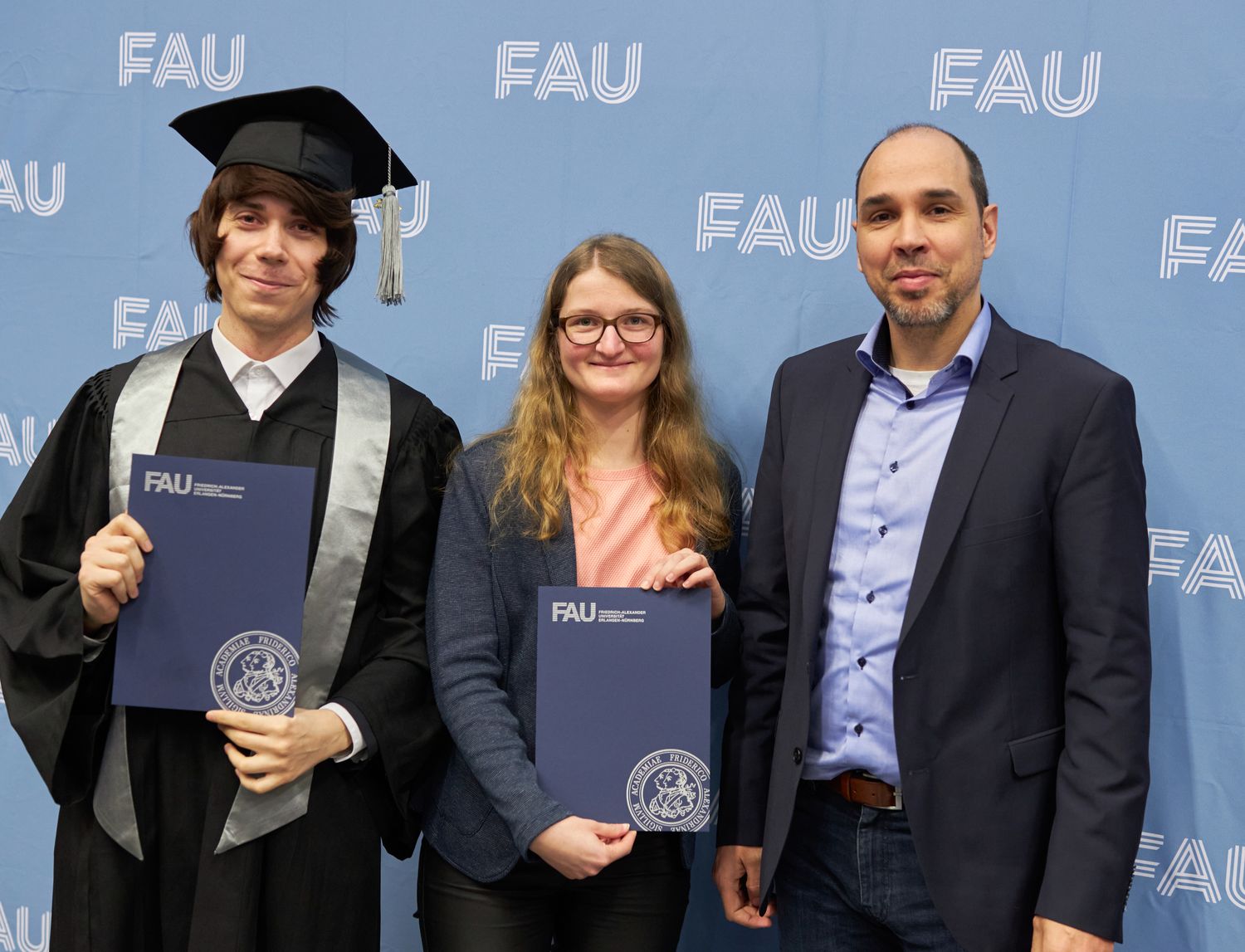 Überreichung der Urkunden an eine Absolventin und einen Absolventen.