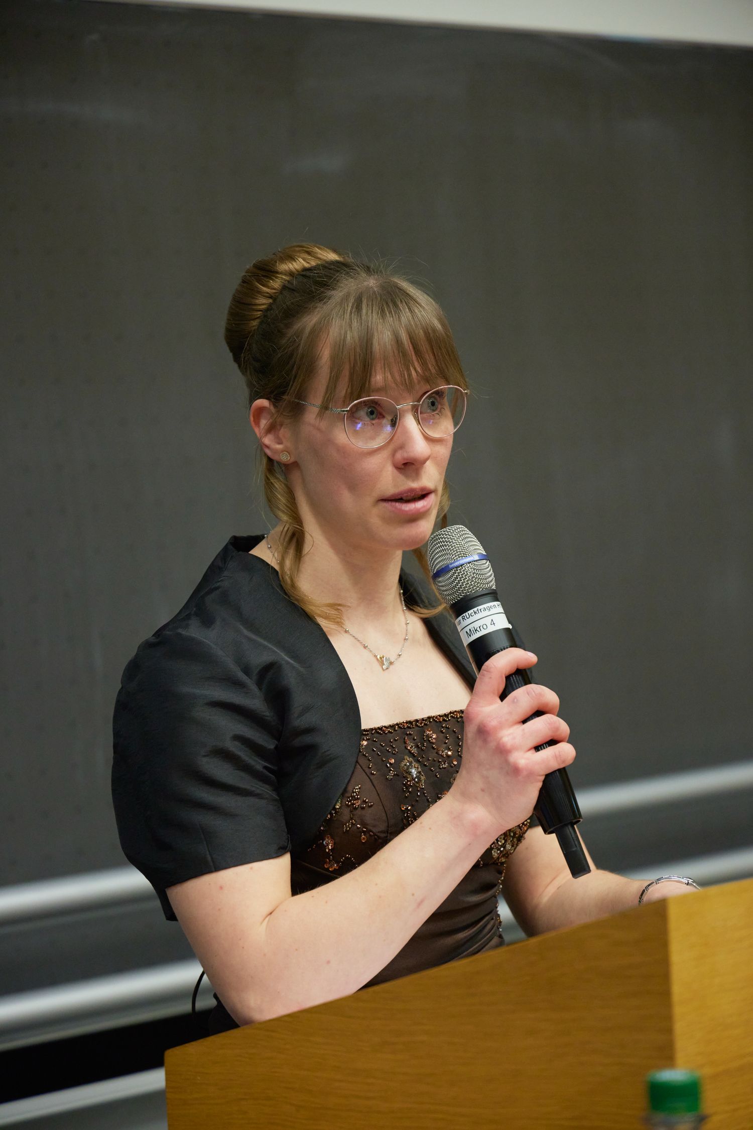 Eine Person hält ein Mikrofon in der Hand und hält eine Rede.