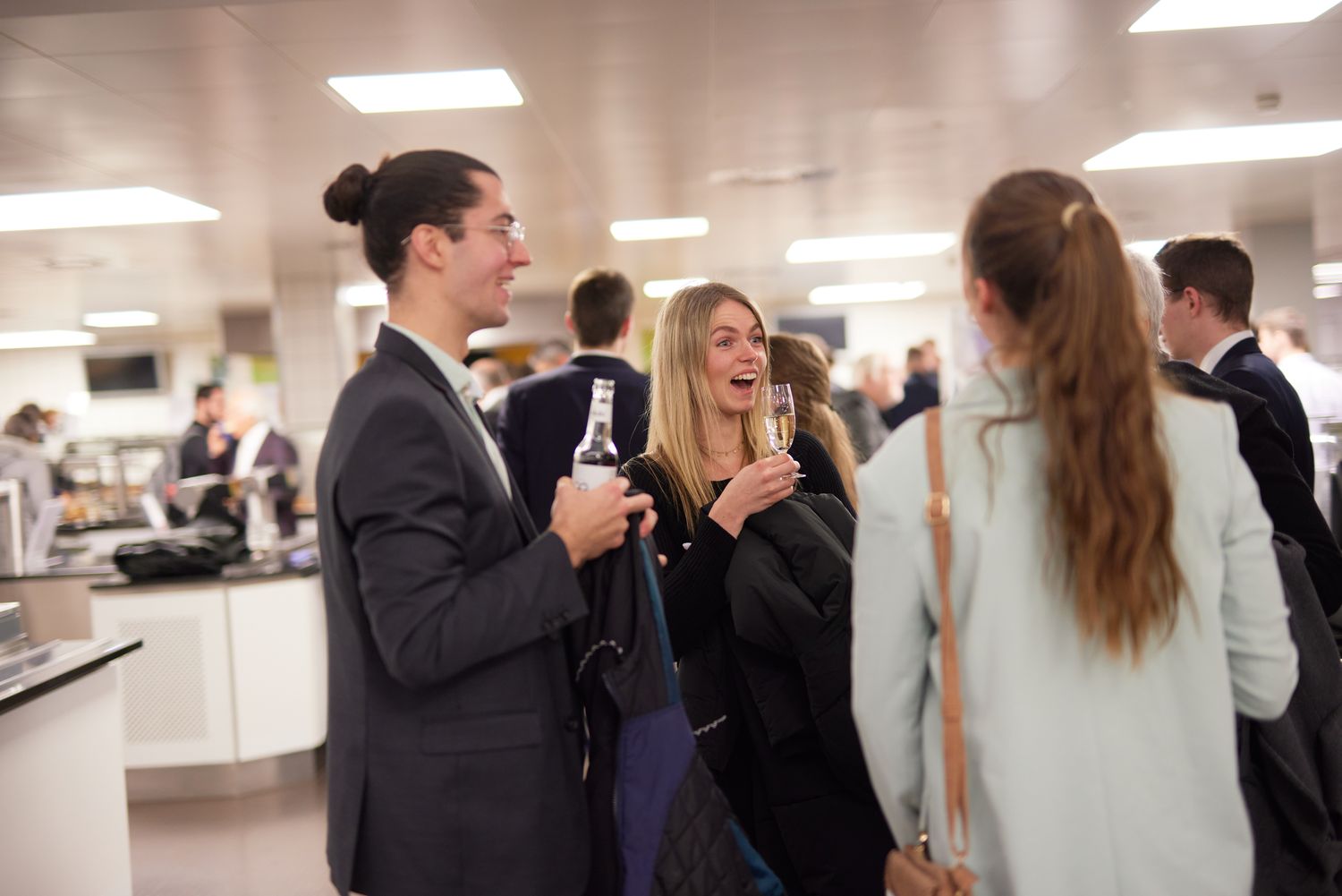 Einige Personen stehen beieinander und unterhalten sich. Zwei halten ein Getränk in der Hand.