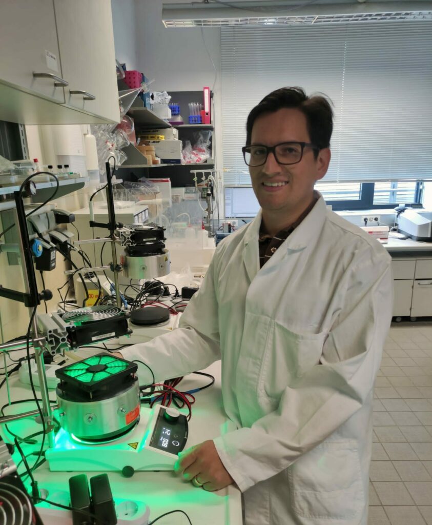 Ein Mann mit Brille und weißem Mantel steht in einem Labor.