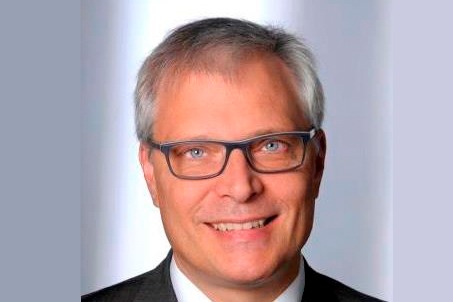 Professor Jürgen Karl schaut lächelnd in die Kamera, er trägt eine Brille.