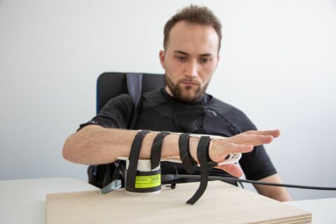 Eine Person testet eine Bewegungsunterstützung am Unterarm.