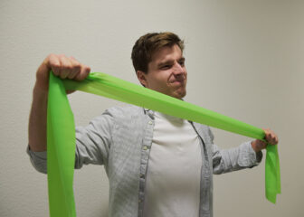 Eine Person zieht ein grünes Gummiband auseinander.