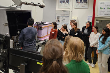 Mehrere Peronen stehen nebeneinander und schauen auf eine Maschine.