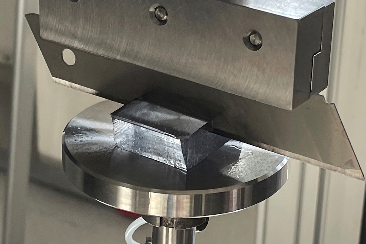 Eine Klinge schneidet in ein Stück Gummi (Elastomer).